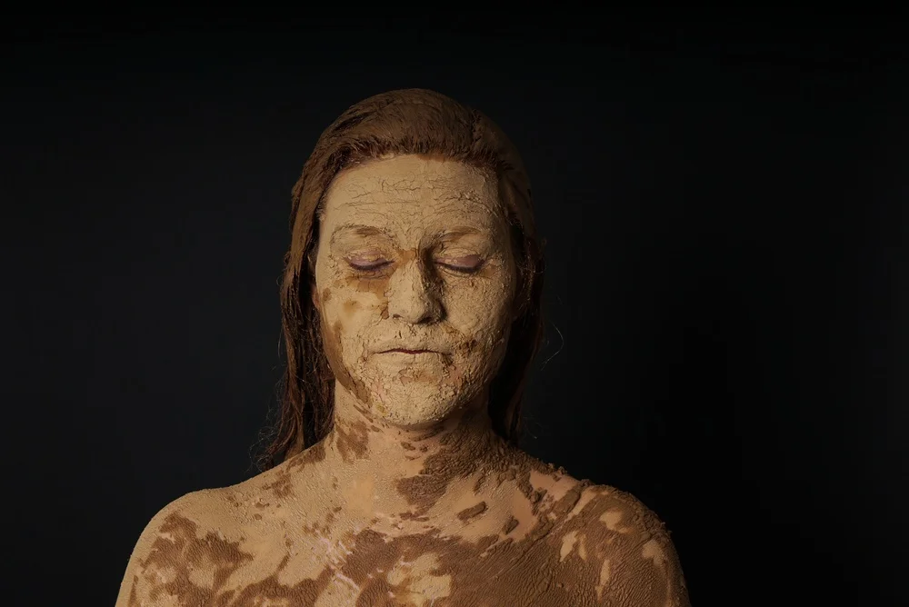 Twarz kobiety pokryta glinianym błotem w klimacie filmu Clayface